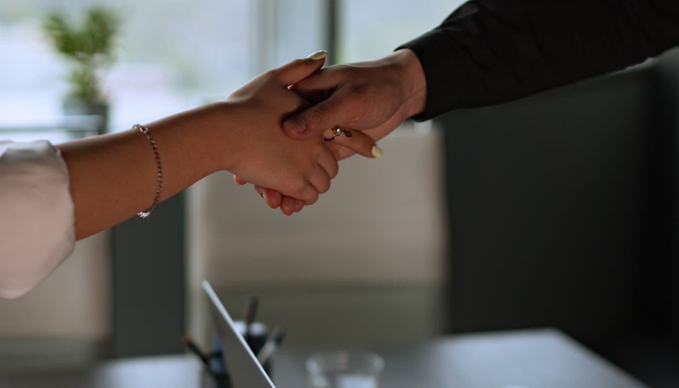 Deux professionnels se serrant la main au-dessus d’un bureau